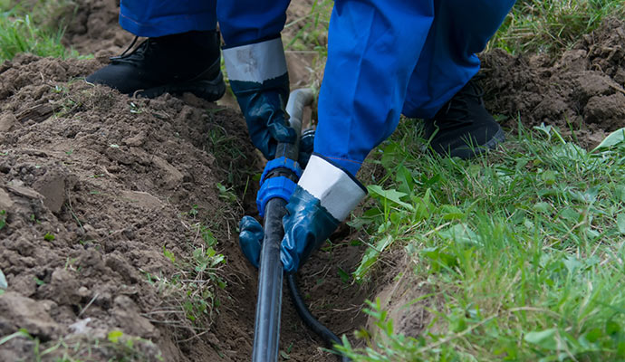 hands of the worker in blue gloves tring to fix incorrect pipe laying