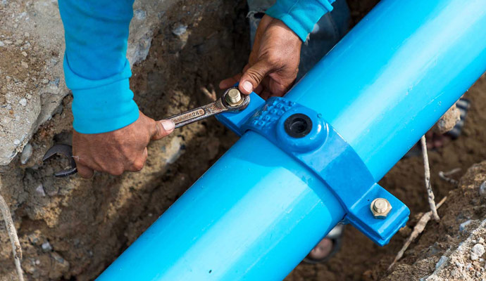 Worker repairing sewage pipe leaks